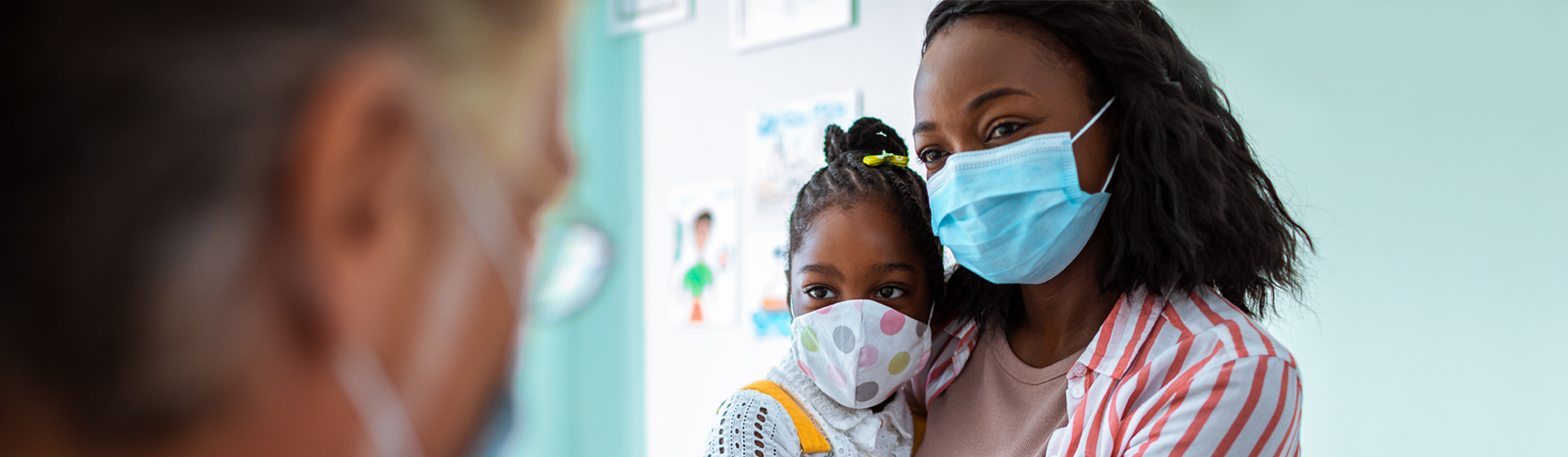 Mother and daughter wearing masks visiting doctor's office