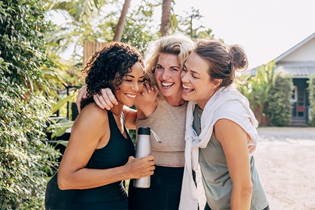 Women in exercise gear laugh together outside
